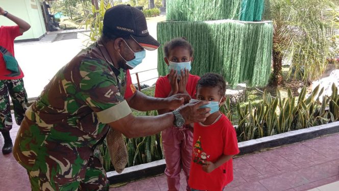 Babinsa Koramil 1710-03/Kuala Kencana Sertu Manse Wanenda membagikan masker gratis kepada Jemaat Gereja, bertempat di Kampung Pioka Kencana Distrik Kuala Kencana, Kab. Mimika, Minggu (19/12/2021). FOTO : PENDAM VII/CENDERAWASIH