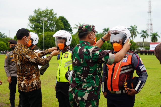 Komandan Korem 042/Gapu Brigjen TNI Supriono, S.IP., M.M secara simbolis memakaikan helm kepada perwakilan peserta Apel Nyata Peningkatan Tertib Berlalu Lintas Provinsi Jambi (Foto. Penrem 042/Gapu)